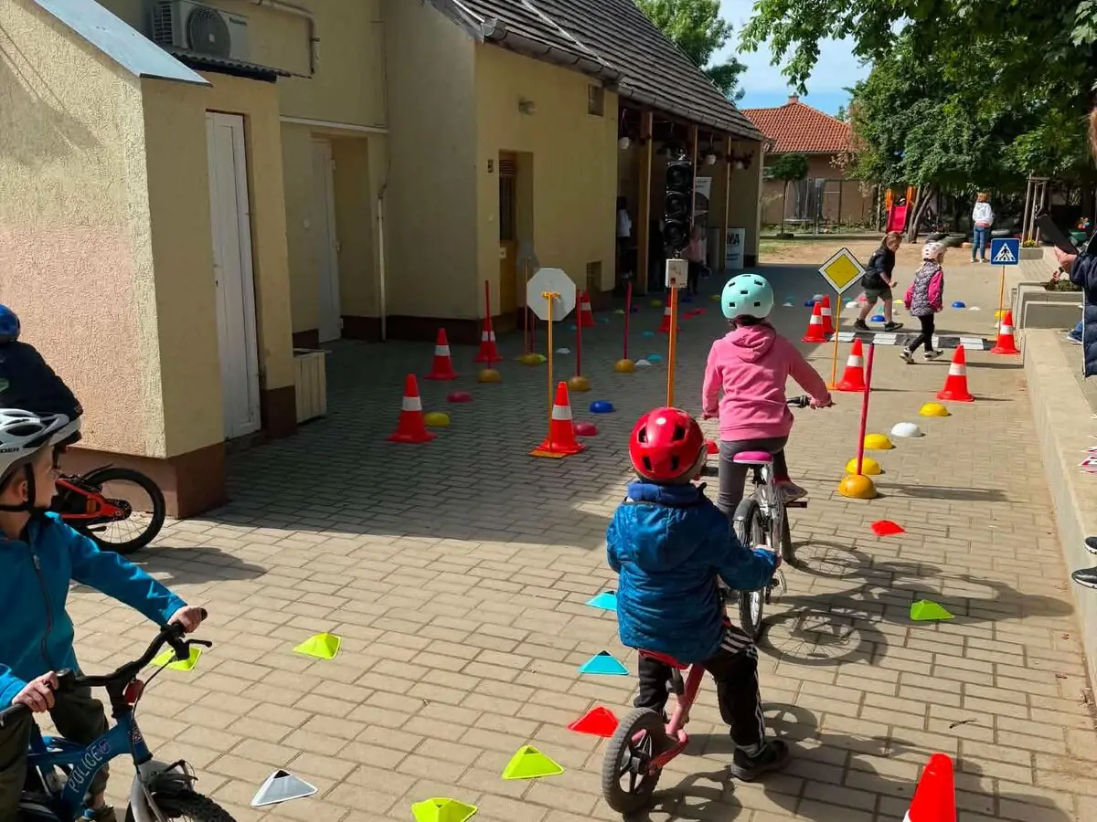 Gyerekek rollerrel és kerékpárral gyakorolnak ügyességi pályán