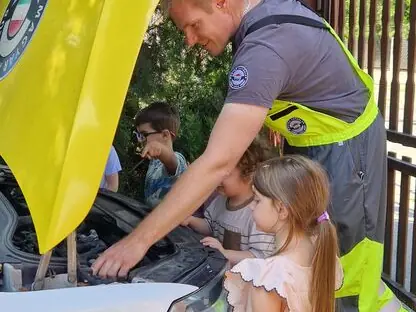 Oktató valós közlekedési helyzetet mutat be gyerekeknek egy autónál